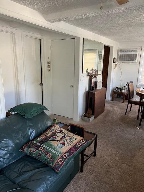 bedroom with a wall mounted air conditioner, carpet flooring, a textured ceiling, and multiple windows