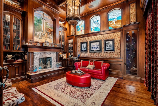 living room with beam ceiling, coffered ceiling, an inviting chandelier, a high end fireplace, and dark hardwood / wood-style floors