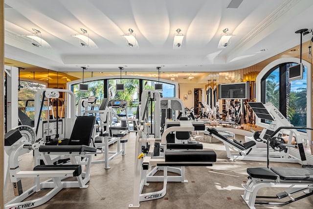 exercise room with a raised ceiling and ornamental molding