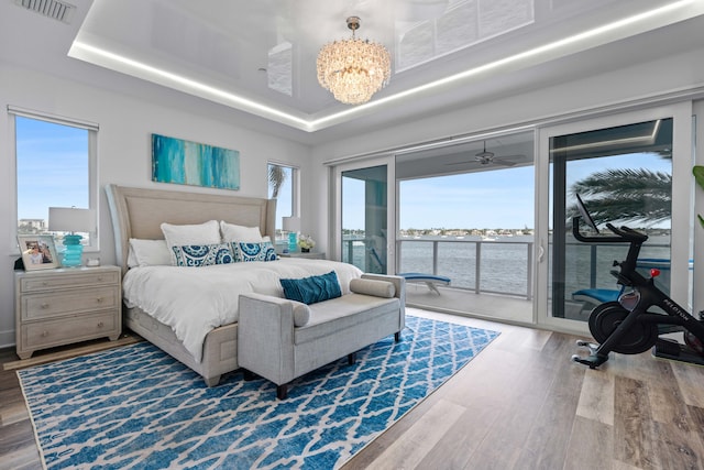 bedroom featuring wood-type flooring, access to outside, multiple windows, and a water view