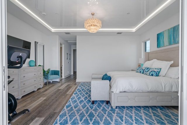 bedroom with dark hardwood / wood-style flooring, a tray ceiling, and a chandelier