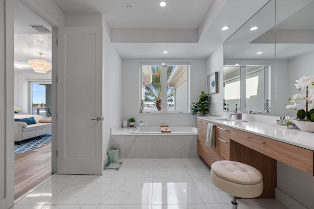 bathroom featuring hardwood / wood-style floors, a notable chandelier, vanity, and tiled tub