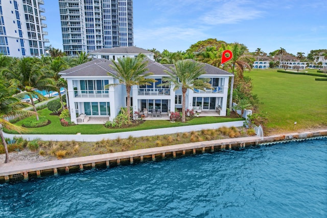 back of property with a lawn, a water view, and a balcony