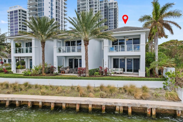 back of property featuring ceiling fan, a patio area, and a water view