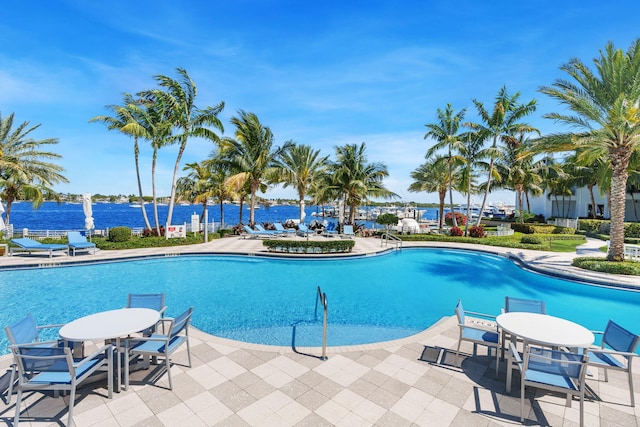 view of swimming pool with a water view and a patio area