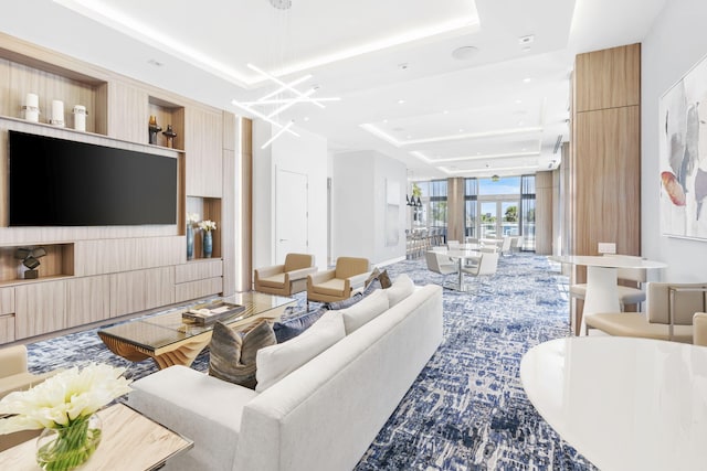 living room featuring a tray ceiling, a chandelier, and a wall of windows