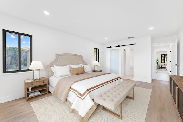 bedroom featuring a barn door and light hardwood / wood-style flooring