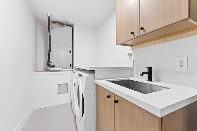 clothes washing area with washing machine and dryer, sink, light tile patterned flooring, and cabinets