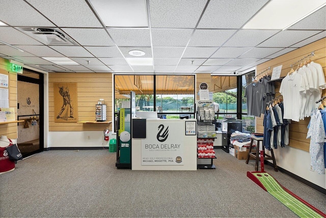 game room featuring carpet flooring, a drop ceiling, and wood walls