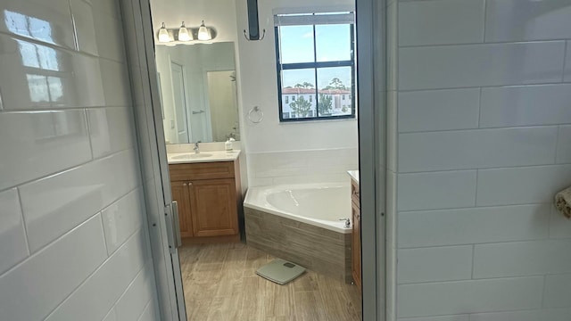 bathroom with vanity, wood-type flooring, and tiled tub