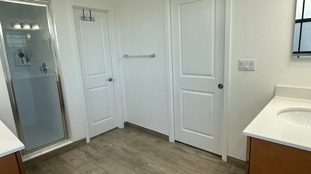 bathroom with walk in shower, vanity, and hardwood / wood-style flooring