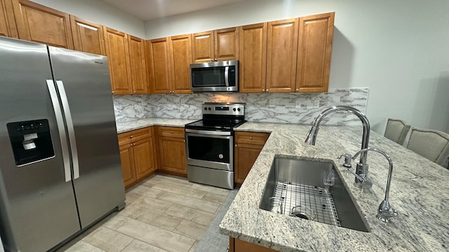 kitchen featuring sink, light stone countertops, kitchen peninsula, and stainless steel appliances