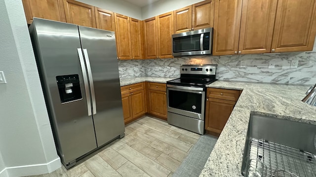 kitchen featuring decorative backsplash, light stone countertops, and appliances with stainless steel finishes