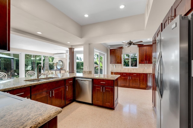 kitchen with backsplash, sink, ceiling fan, light stone counters, and stainless steel appliances