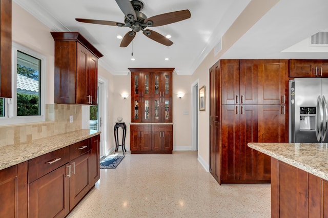 kitchen featuring stainless steel fridge, tasteful backsplash, light stone counters, ornamental molding, and ceiling fan