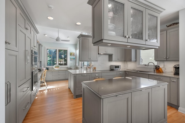 kitchen featuring gray cabinetry, a kitchen island, light hardwood / wood-style floors, and sink