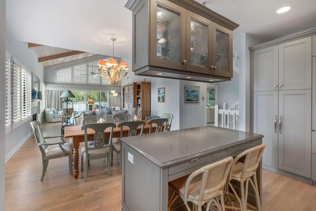 kitchen with vaulted ceiling with beams, pendant lighting, a chandelier, gray cabinets, and light wood-type flooring