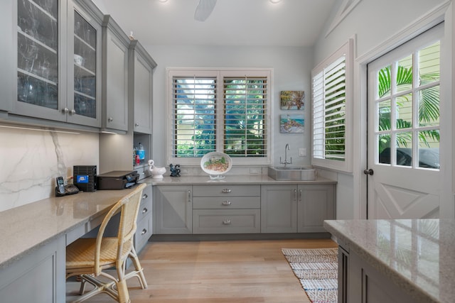 kitchen with gray cabinets, light stone counters, tasteful backsplash, and sink