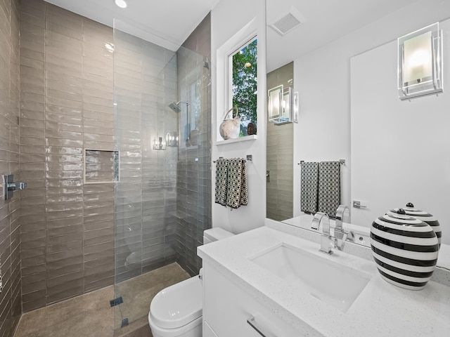 bathroom with vanity, toilet, and a tile shower