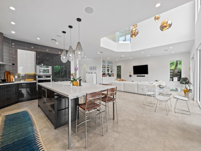 kitchen with a spacious island, a breakfast bar area, decorative light fixtures, appliances with stainless steel finishes, and backsplash