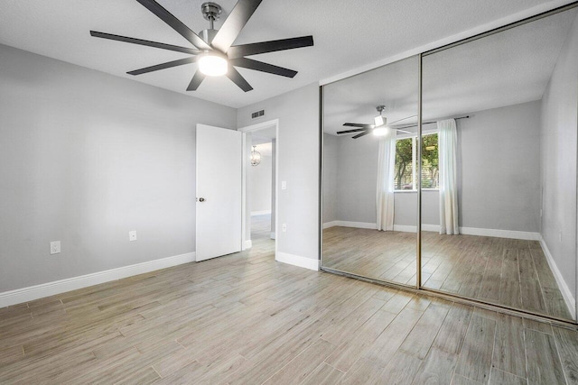 unfurnished bedroom featuring a textured ceiling, a closet, ceiling fan, and light hardwood / wood-style floors