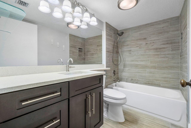 full bathroom featuring vanity, a textured ceiling, hardwood / wood-style floors, toilet, and tiled shower / bath