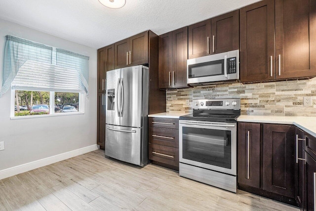 kitchen with appliances with stainless steel finishes, light wood-type flooring, tasteful backsplash, and dark brown cabinets