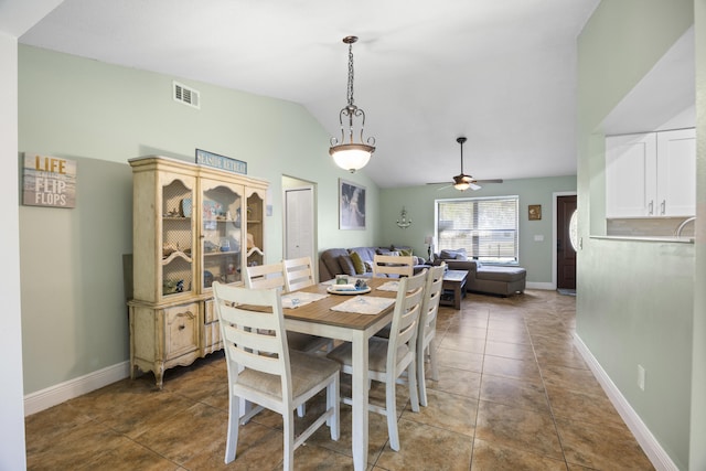 dining space featuring ceiling fan, dark tile patterned floors, and lofted ceiling