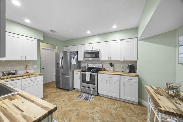 kitchen featuring white cabinets, backsplash, stainless steel appliances, and butcher block counters