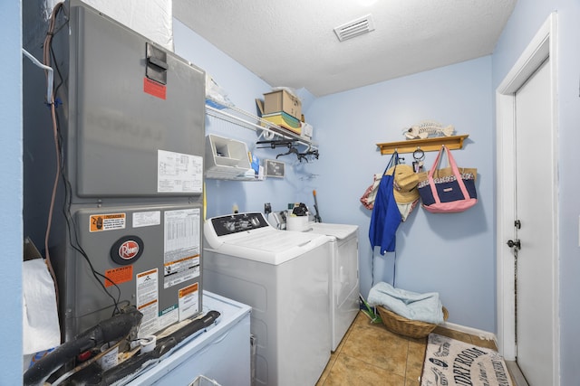 laundry room featuring independent washer and dryer, a textured ceiling, heating unit, and light tile patterned floors