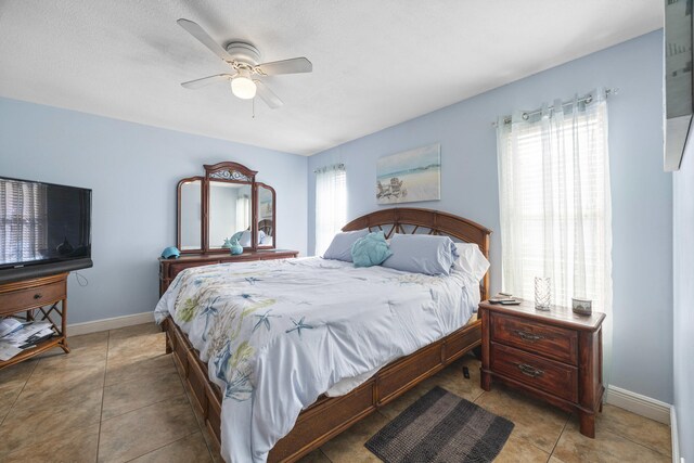 tiled bedroom with ceiling fan and multiple windows