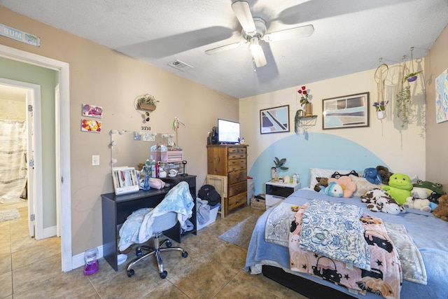 bedroom featuring ceiling fan, tile patterned flooring, ensuite bathroom, and a textured ceiling