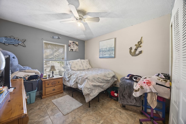 tiled bedroom with a textured ceiling and ceiling fan