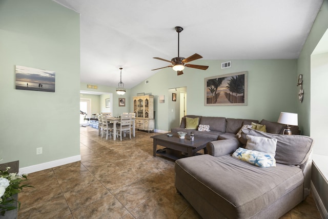 living room with ceiling fan, dark tile patterned floors, and vaulted ceiling