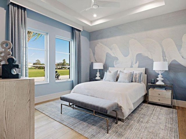 bedroom with wood-type flooring, a tray ceiling, and ceiling fan