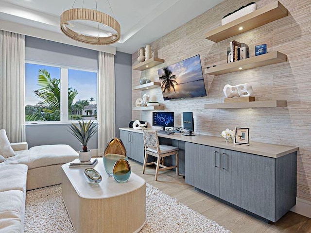 interior space featuring light hardwood / wood-style floors, a raised ceiling, and built in desk