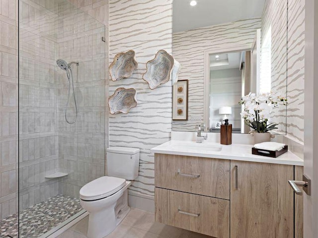 bathroom featuring vanity, toilet, tile walls, and a tile shower