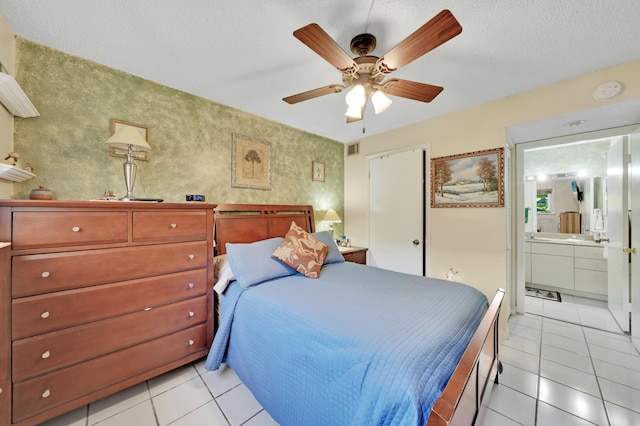 bedroom with a textured ceiling, ensuite bathroom, ceiling fan, and light tile patterned floors