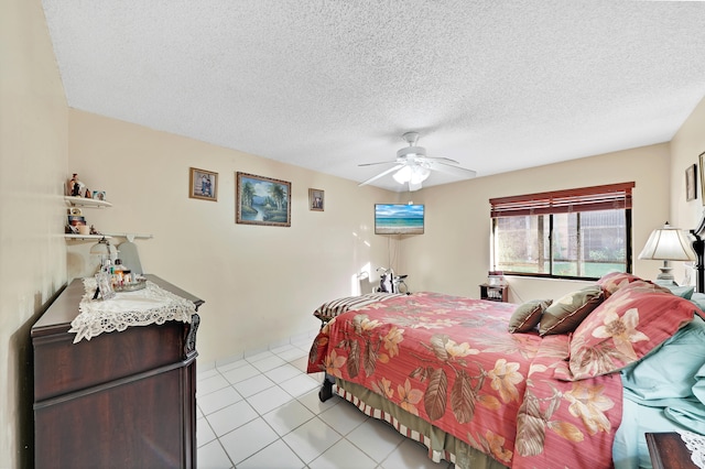 bedroom featuring ceiling fan, light tile patterned floors, and a textured ceiling