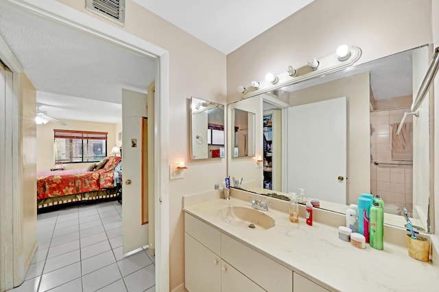 bathroom featuring a textured ceiling, vanity, ceiling fan, tiled shower, and tile patterned flooring