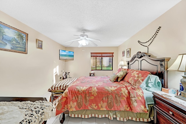 bedroom with ceiling fan, light tile patterned floors, and a textured ceiling