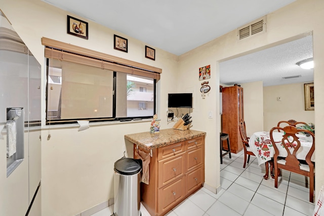 kitchen featuring light tile patterned floors, a textured ceiling, and light stone counters