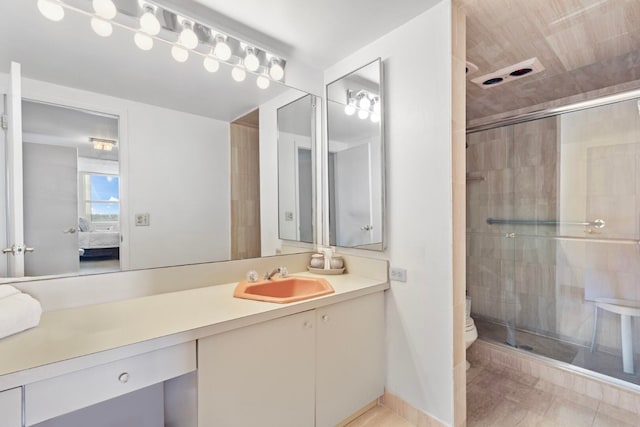 bathroom featuring an enclosed shower, vanity, toilet, and tile patterned flooring