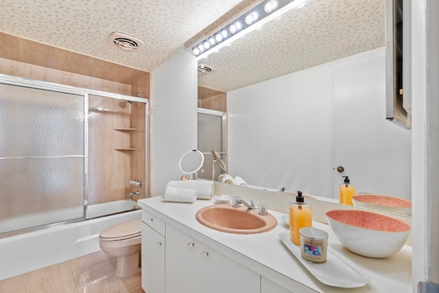 full bathroom with shower / bath combination with glass door, tile patterned floors, vanity, and toilet