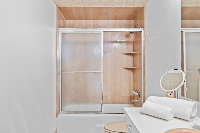 full bathroom with vanity, bath / shower combo with glass door, and toilet