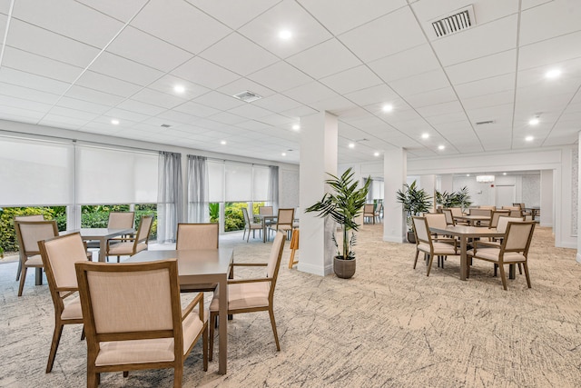 dining space featuring light carpet and a drop ceiling