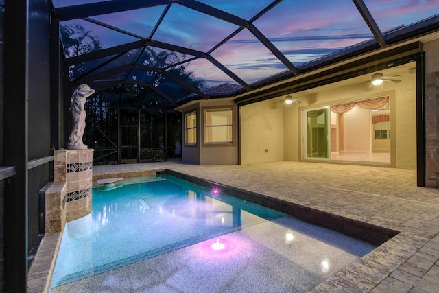 pool at dusk featuring a patio area, ceiling fan, and a lanai