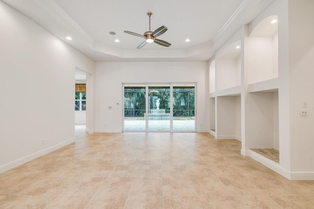 empty room featuring a raised ceiling, ceiling fan, a towering ceiling, and ornamental molding