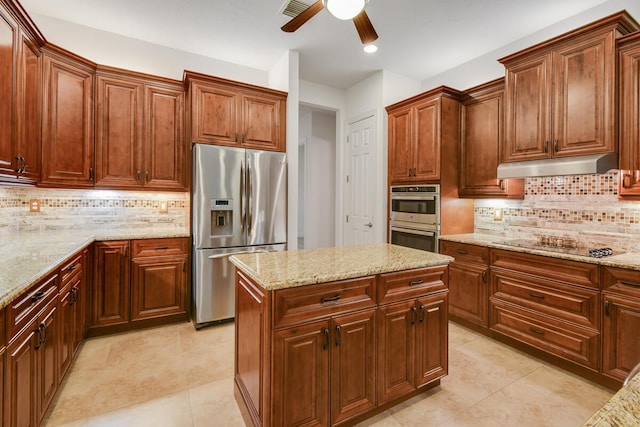 kitchen with appliances with stainless steel finishes, a center island, light stone counters, and backsplash