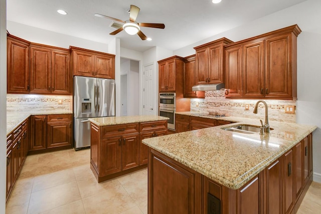 kitchen featuring light stone countertops, decorative backsplash, stainless steel appliances, sink, and a center island